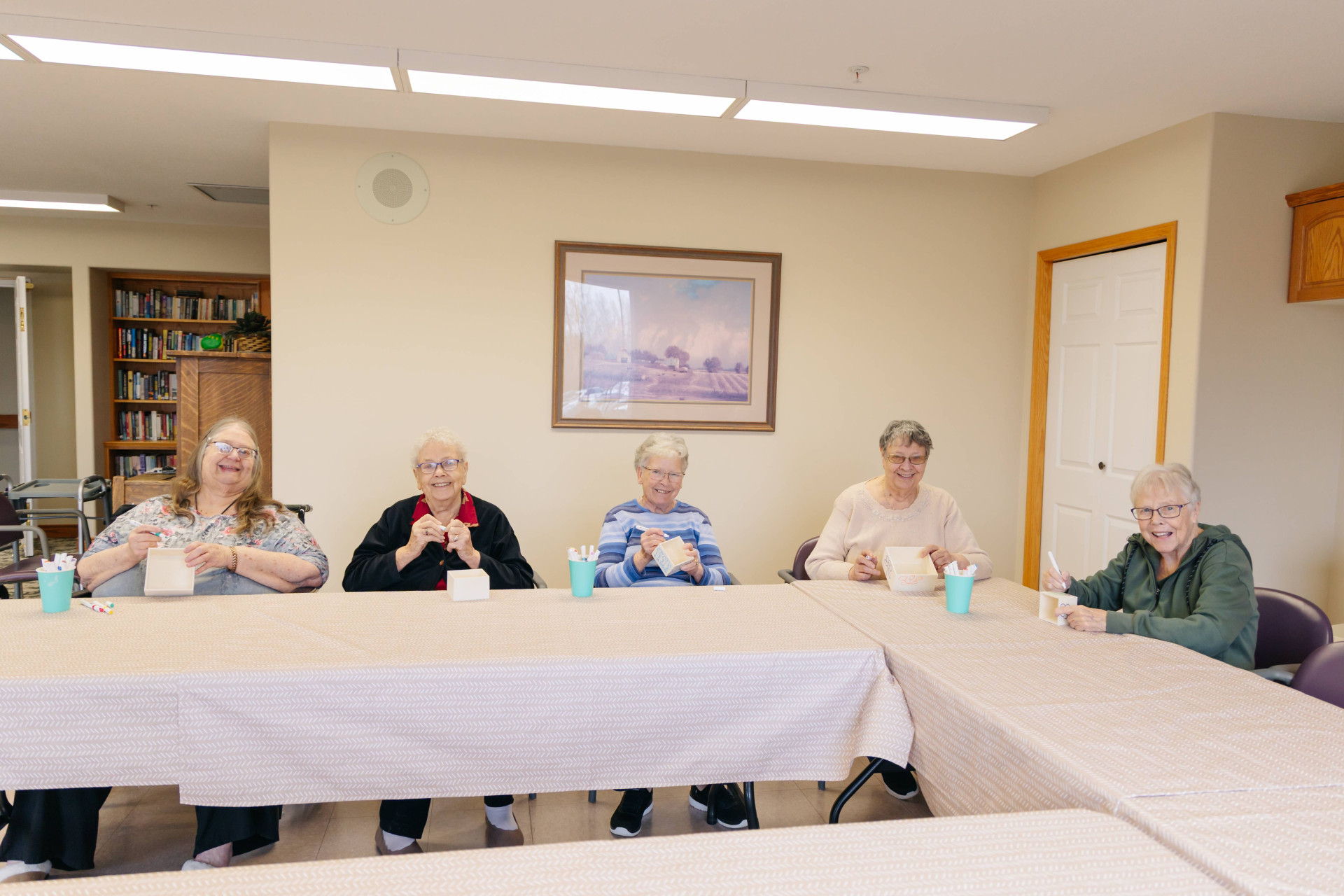 Senior women enjoying a group craft activity at a table in the Harvest House common room, Olds Alberta